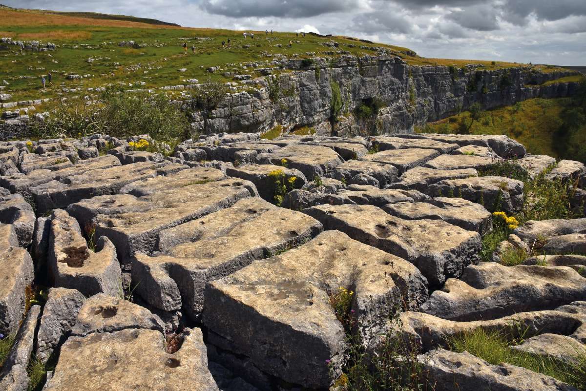 Malham Cove – Egy meredek, sziklás letörés tetején, a közel vízszintes mészkőrétegeket látványosan szabdalják blokkokra a függőleges repedések. Ez Anglia egyik legnépszerűbb karrjárdás helyszíne. Nemcsak a turisták, hanem a filmesek is kedvelik: itt forgattak néhány jelenetet például a Harry Potter és a Halál ereklyéi című filmből Fotó: Telbisz Tamás